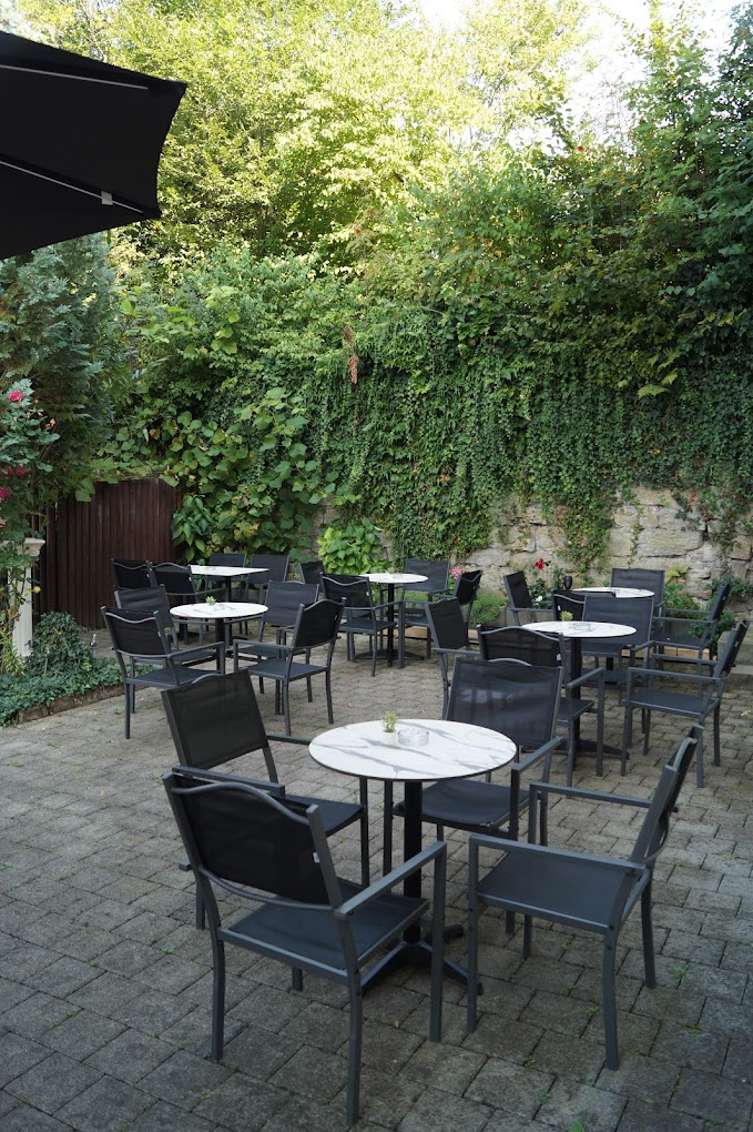 Begrünter Biergarten des Point Cafe Bar bei Tag mit Sitzplätzen und Sonnenschirm