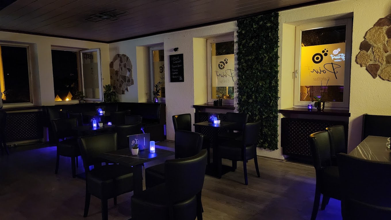 Warmes Innenambiente im Point Cafe Bar mit Kerzen, Efeu-Wand und Point-Fensterlogo